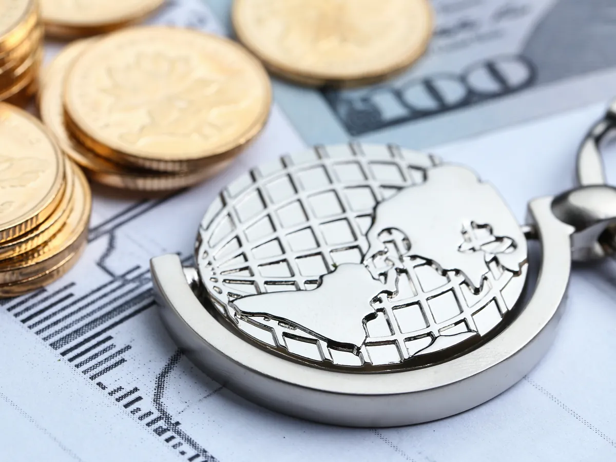 Globo terráqueo metálico sobre monedas y reportes financieros